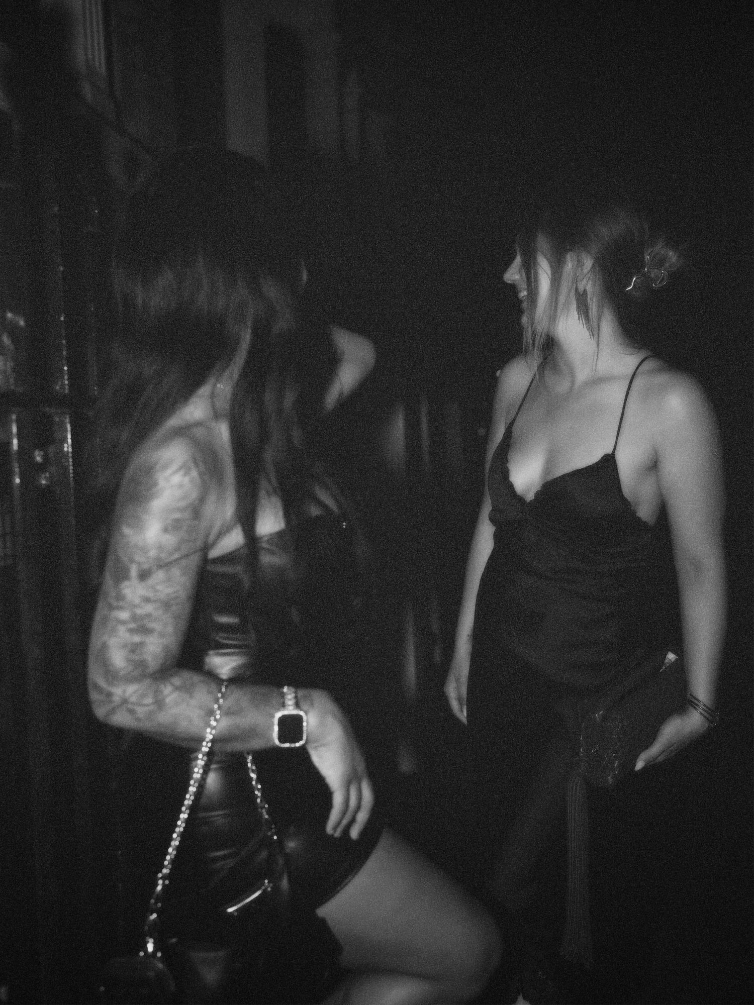 Black and white photograph of two women dancing at nightclub event by ARIETA Studios.