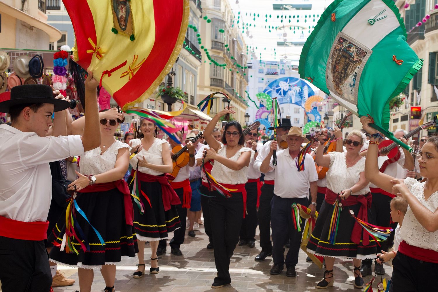 Traditional Verdiales dancers and musicians performing in colorful Andalusian attire on the streets of Málaga.