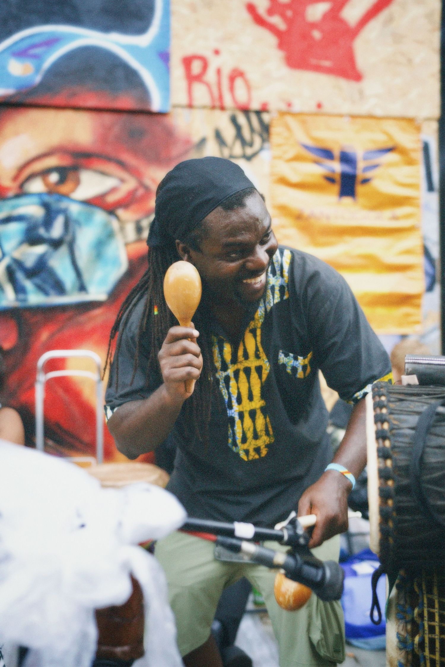 Man playing instruments at the Carnival against a vibrant painted mural wall.