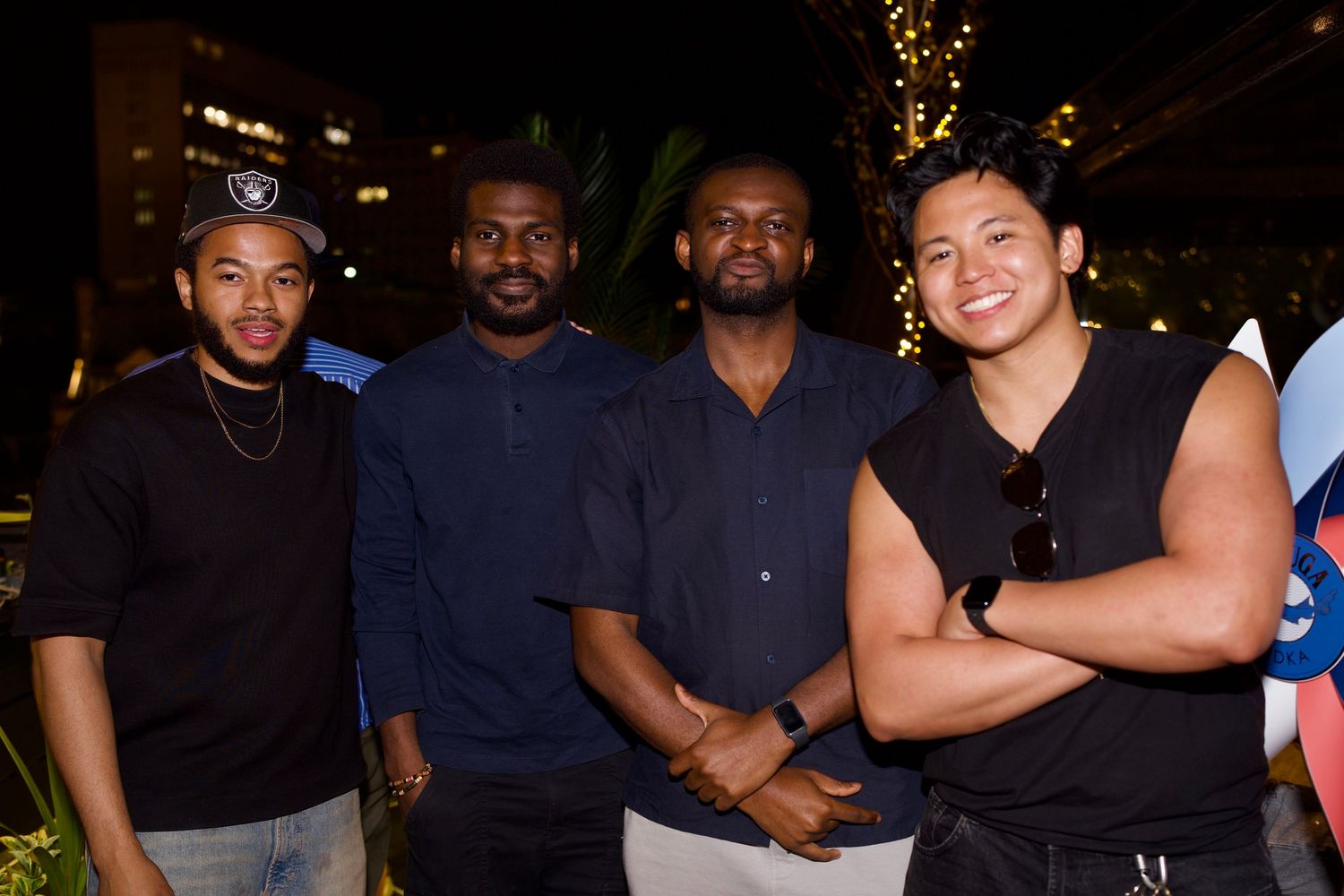 A group of stylish men posing together at an upscale London rooftop venue evening event, by ARIETA STUDIOS.