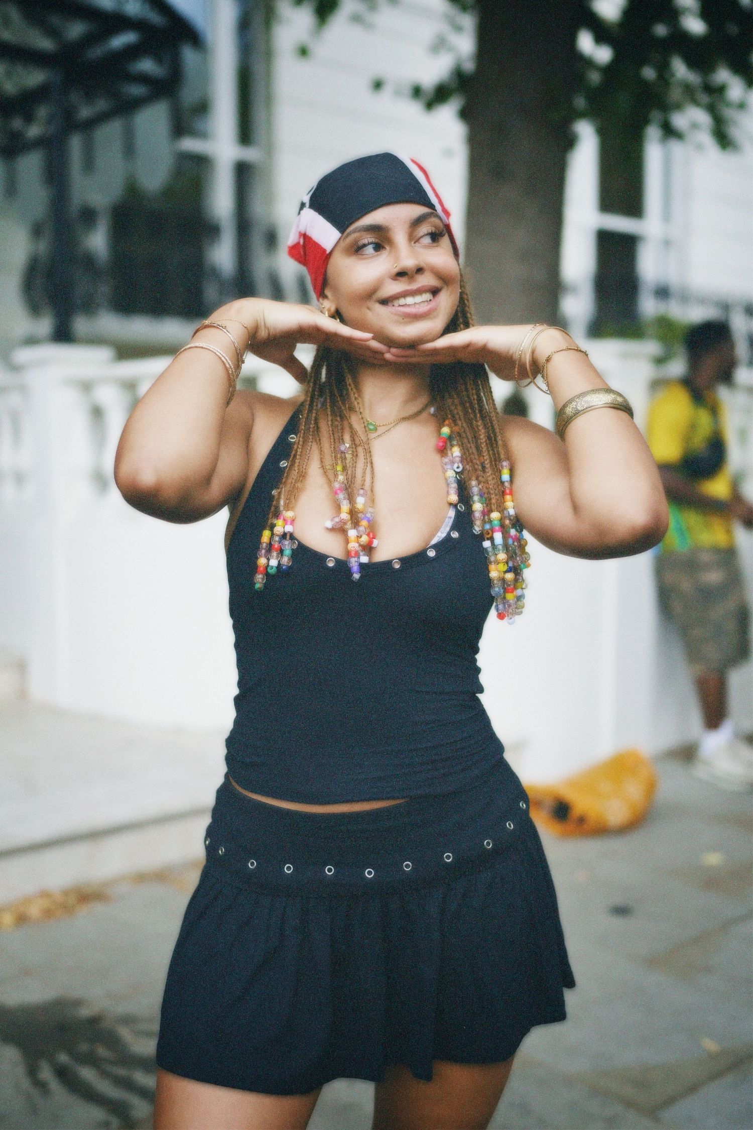 Street style portrait of a model wearing a black tank top, necklace, and patterned headscarf.