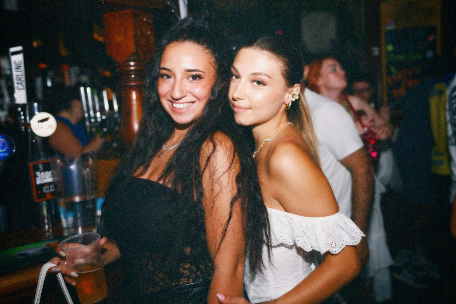 Two women posing together by the bar at London venue event by ARIETA Studios.