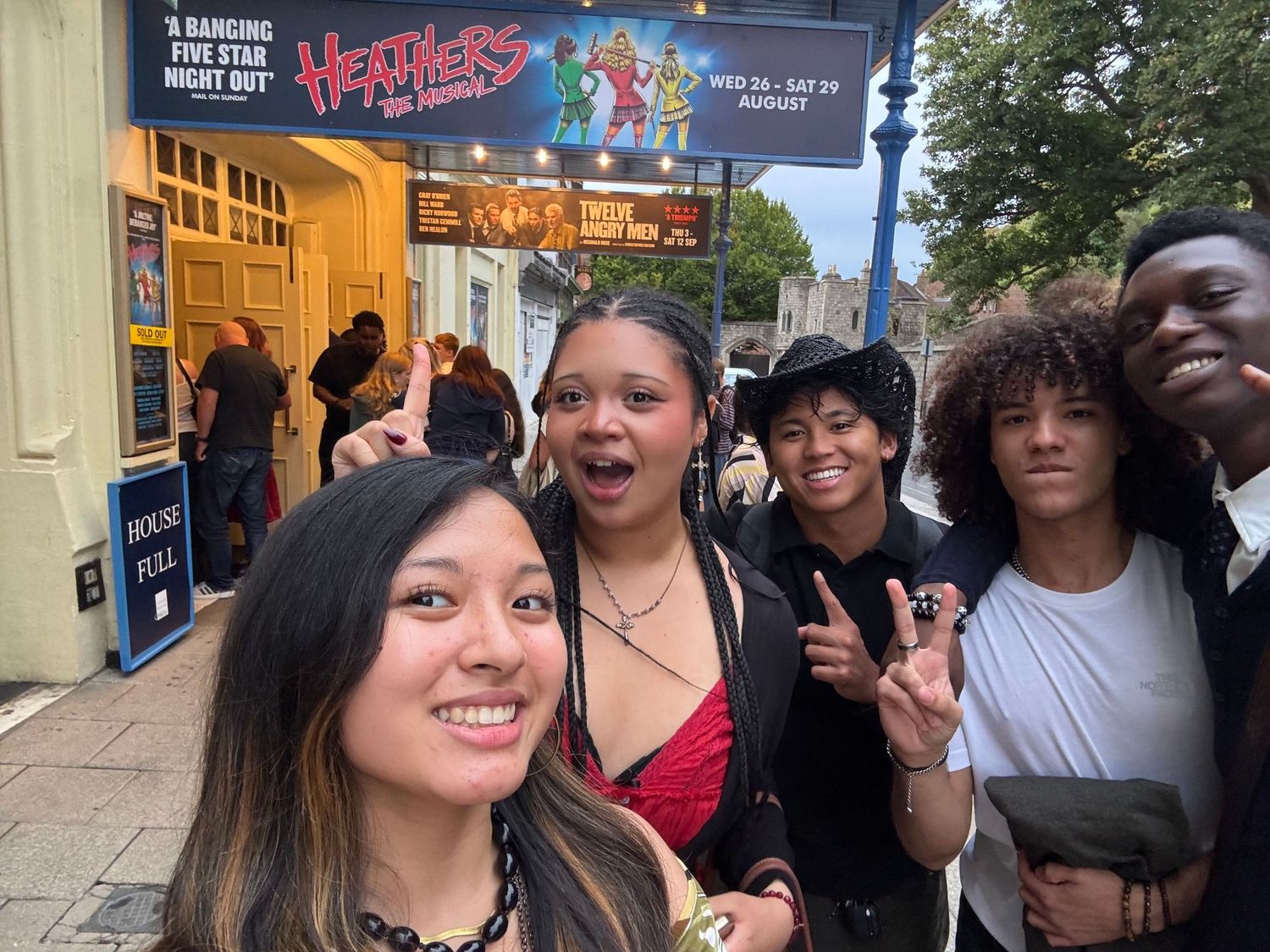 Group selfie outside the theatre doors under the Heathers The Musical sign.