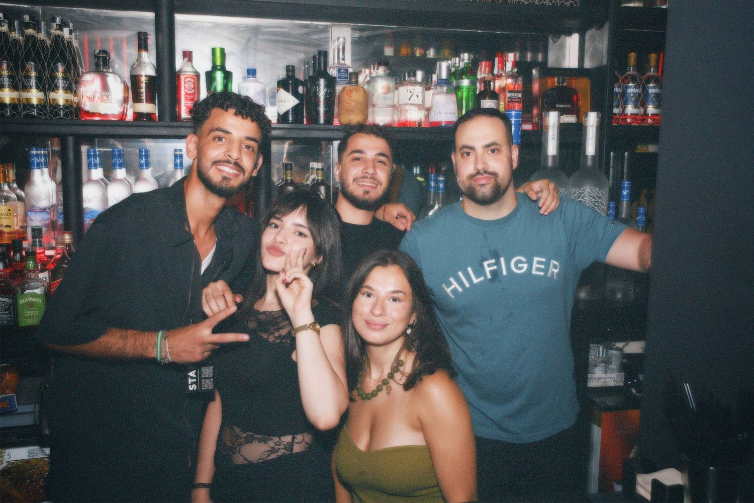 Team smiling together behind the bar. / Personal y equipo sonriendo juntos tras la barra del club.