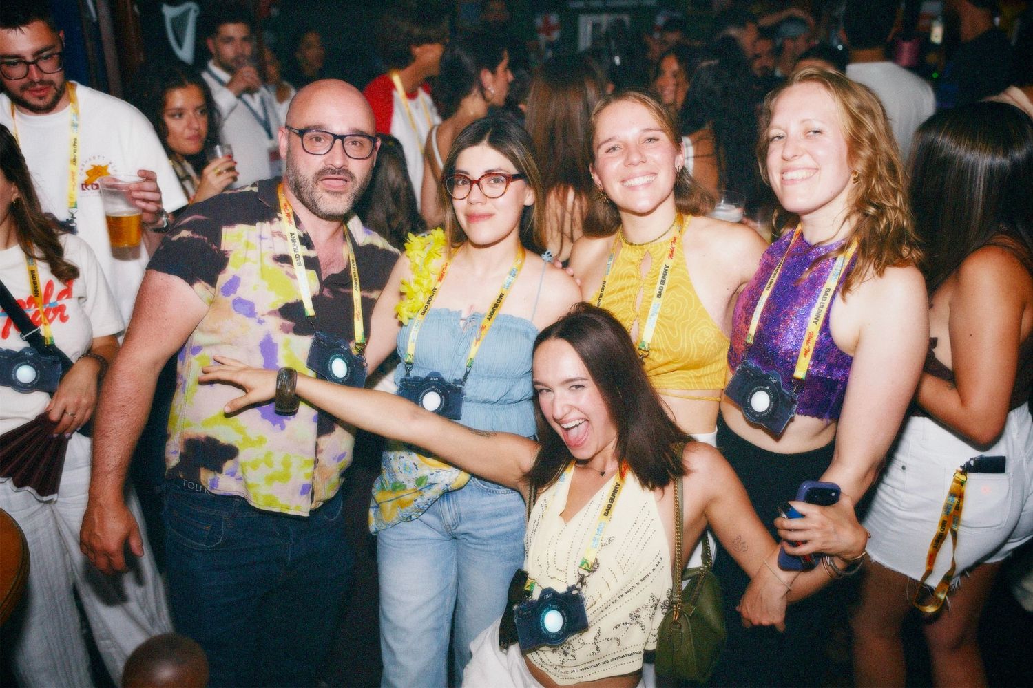 Group of friends posing together on crowded nightclub dancefloor by ARIETA Studios.