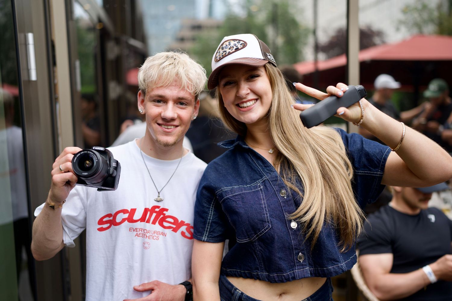A videographer with a camera and a smiling woman posing outside a London event venue space. Captured by ARIETA Studios.