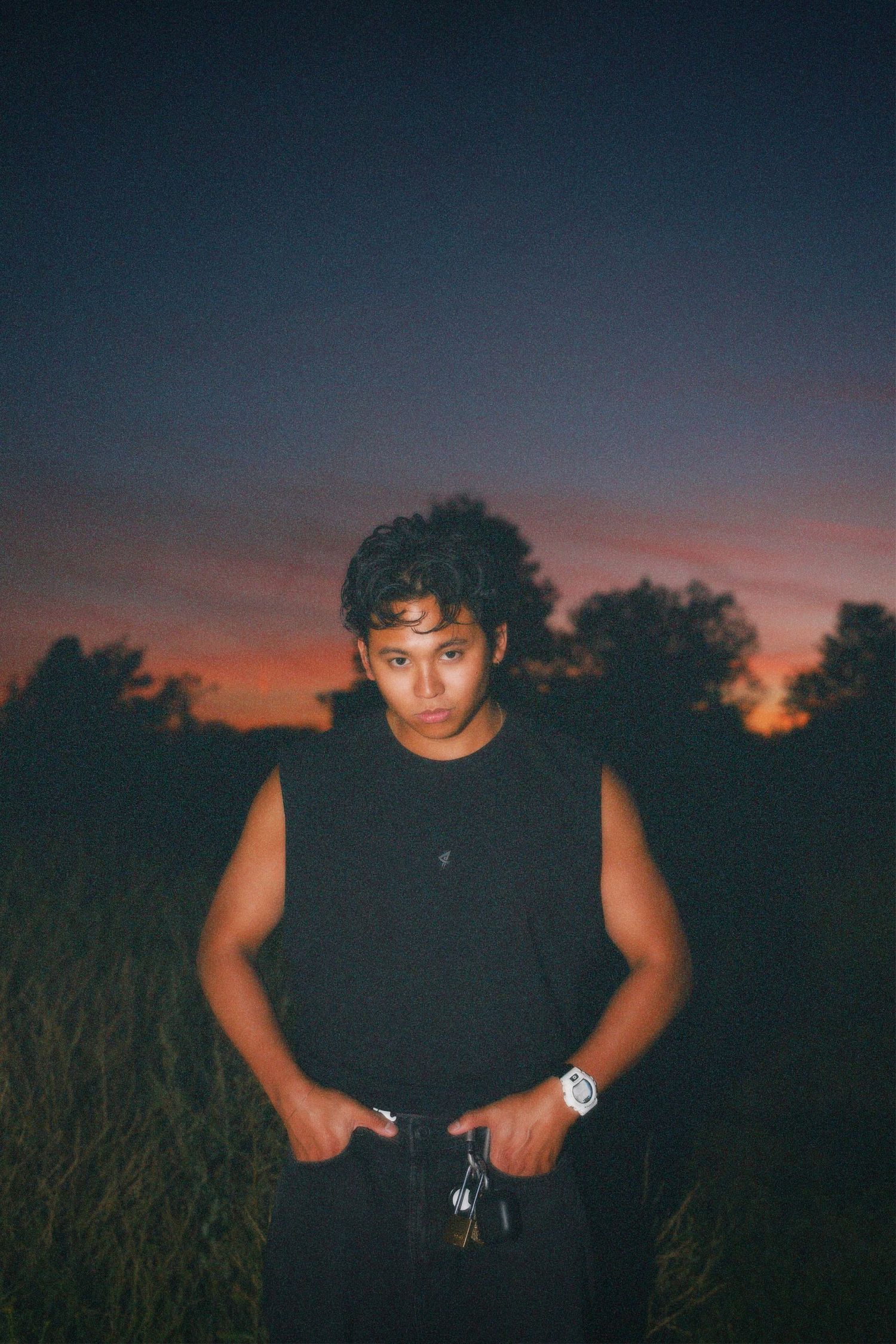 Moody outdoor portrait of Alastair Arieta, founder of Arieta Stuidos standing against a twilight sunset sky.