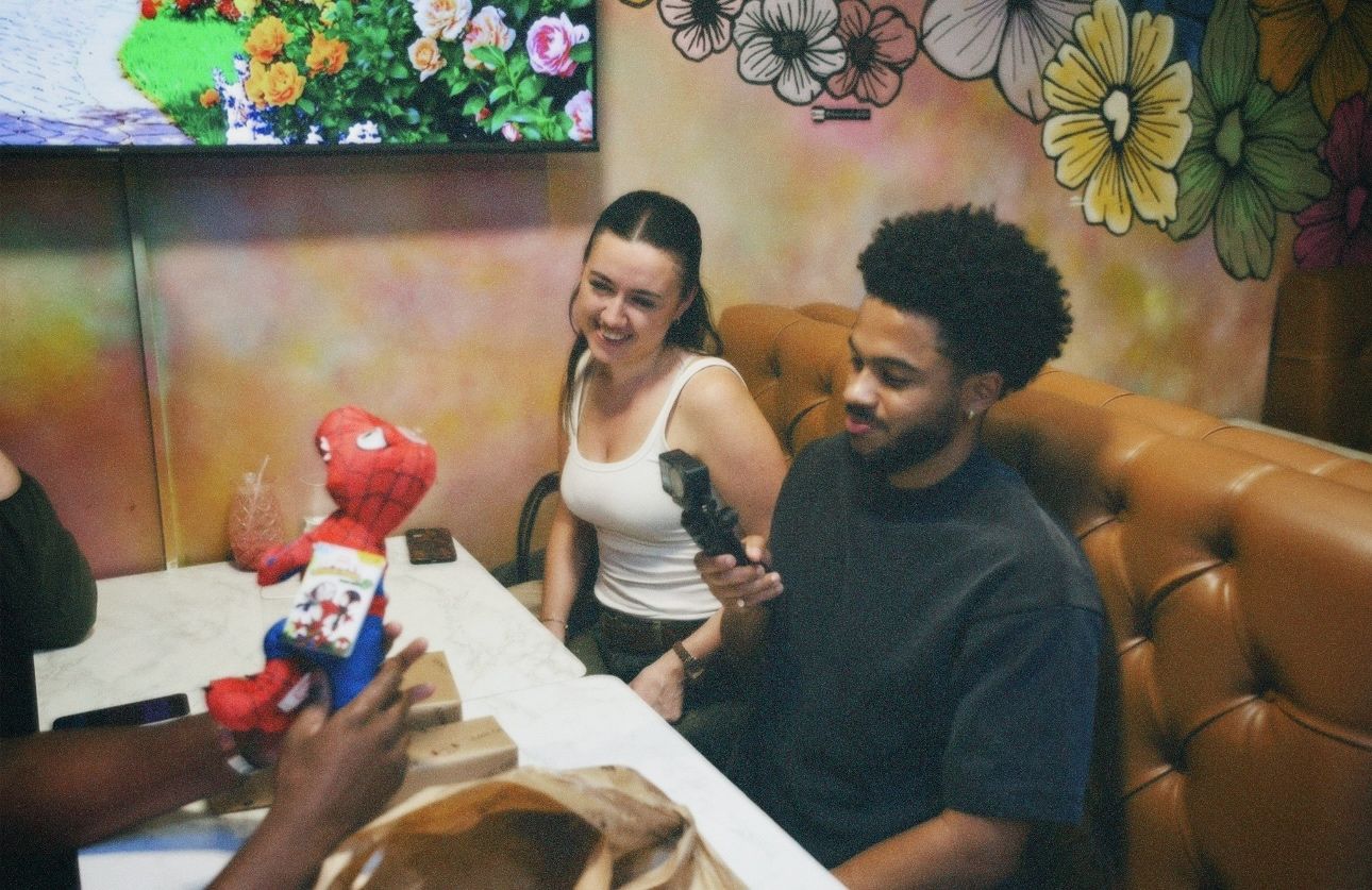 Candid shot of Habeeb and Laura, long-term lovers seated and talking around a dinner table during an evening event.