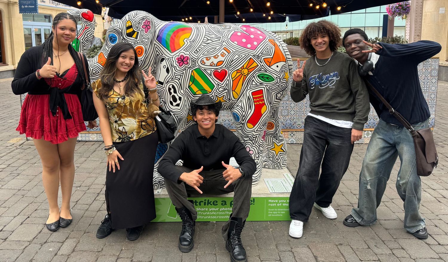The group posing together around a colourful painted elephant sculpture.