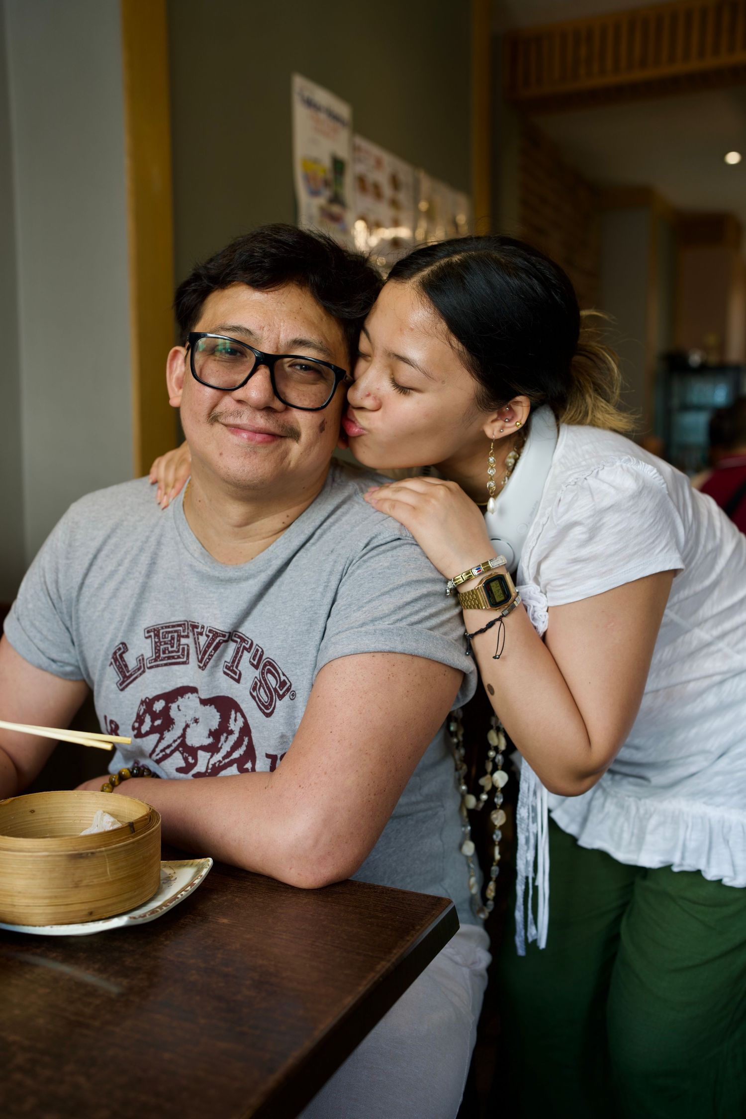 Two side-by-side candid portraits of a family sharing affectionate moments and smiling inside an authentic restaurant.