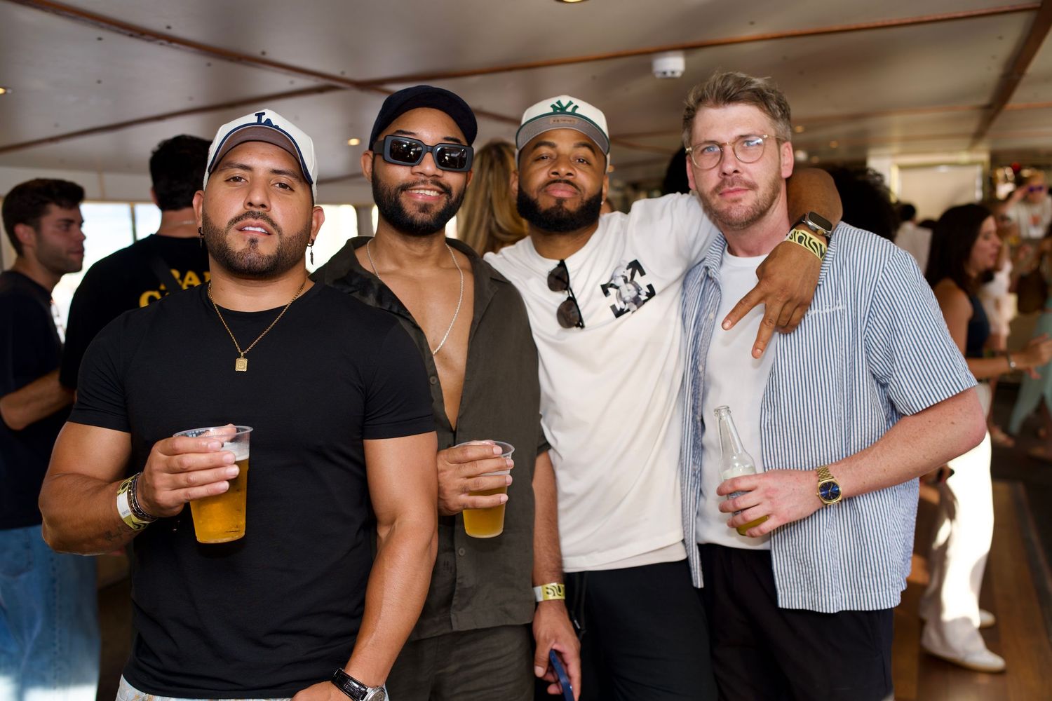 Four men holding drinks and posing inside London river boat event by ARIETA Studios.