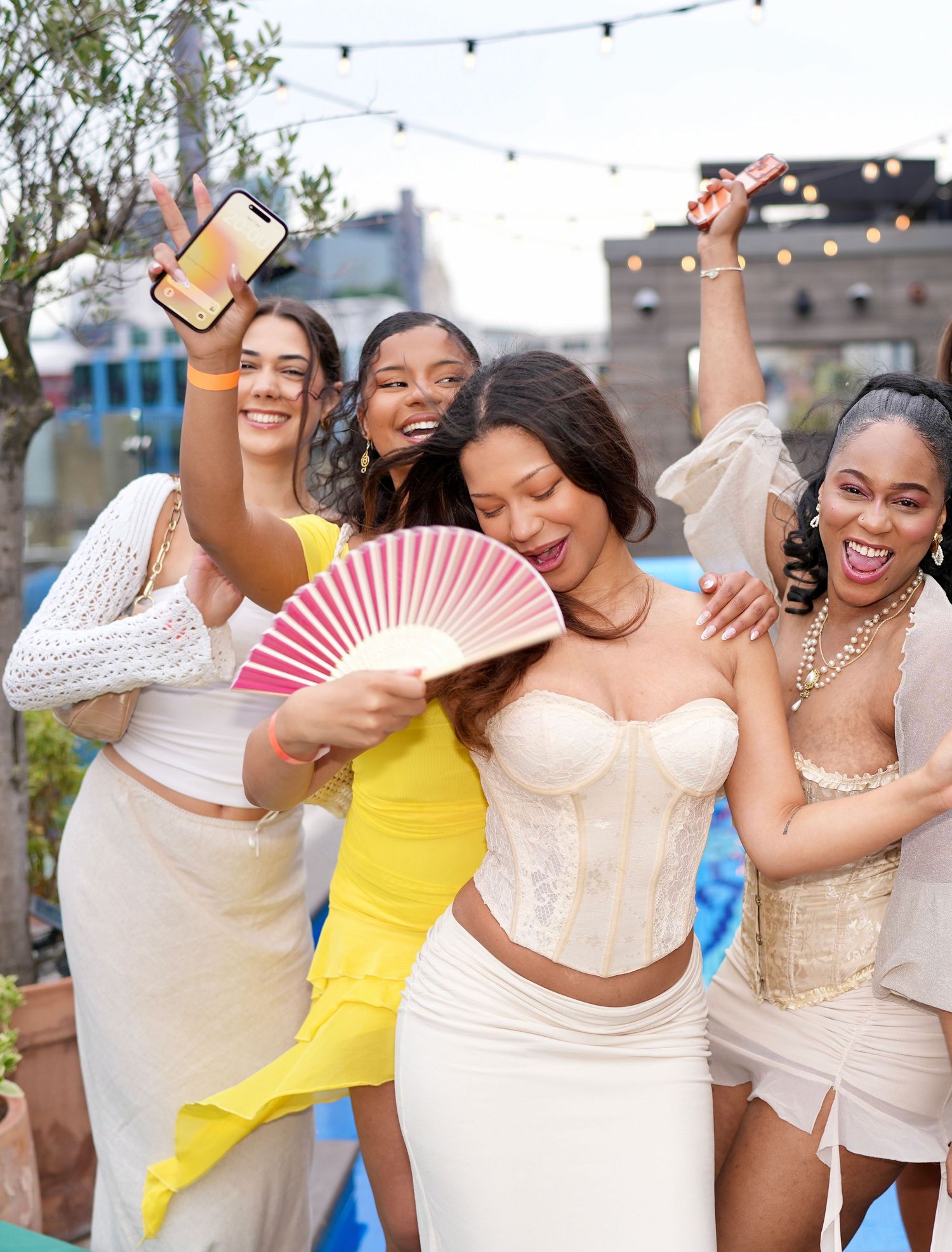 Group of friends celebrating and posing outdoors at daytime party by ARIETA Studios.