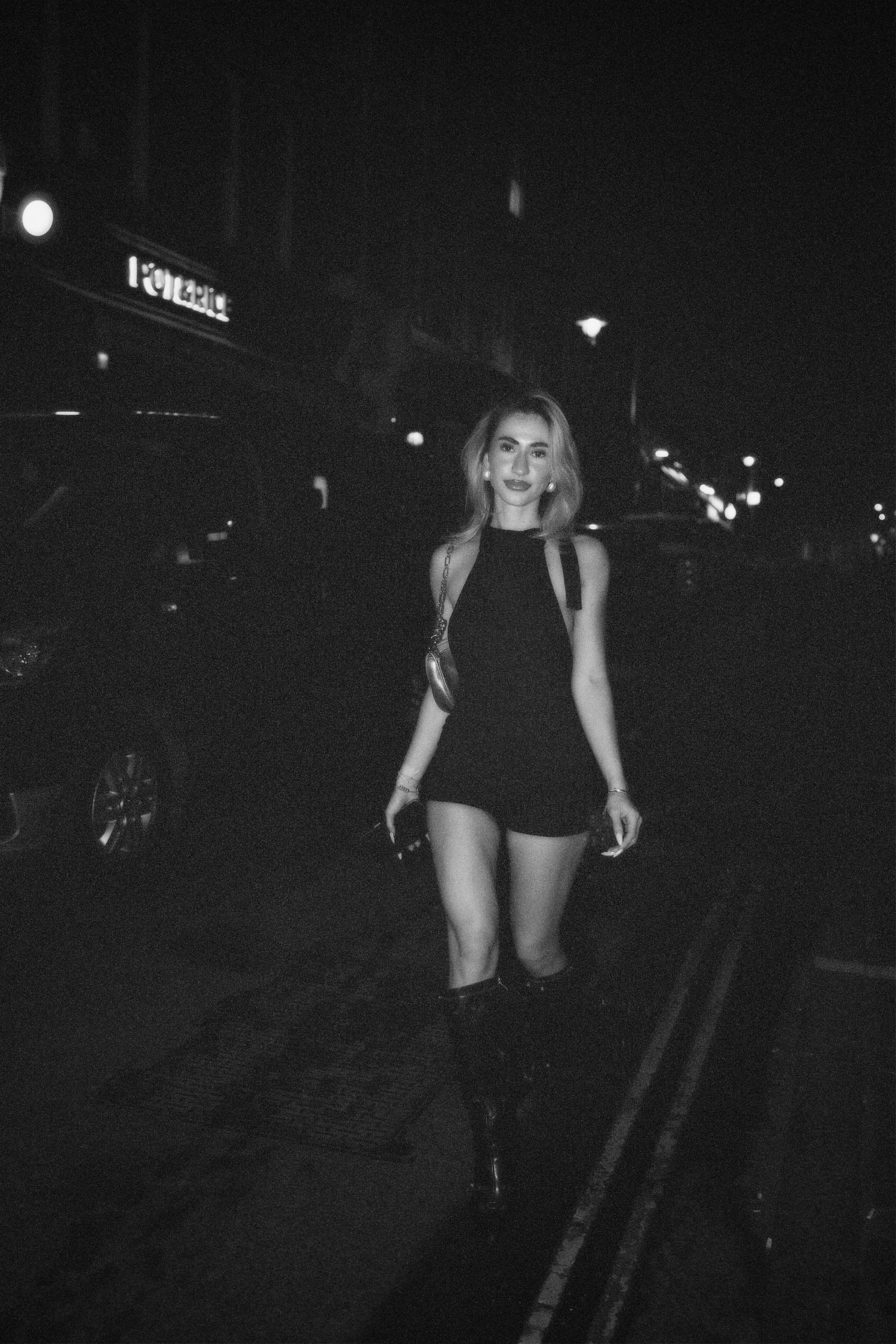 Full length black and white photo of woman walking outdoors at night captured by ARIETA Studios.