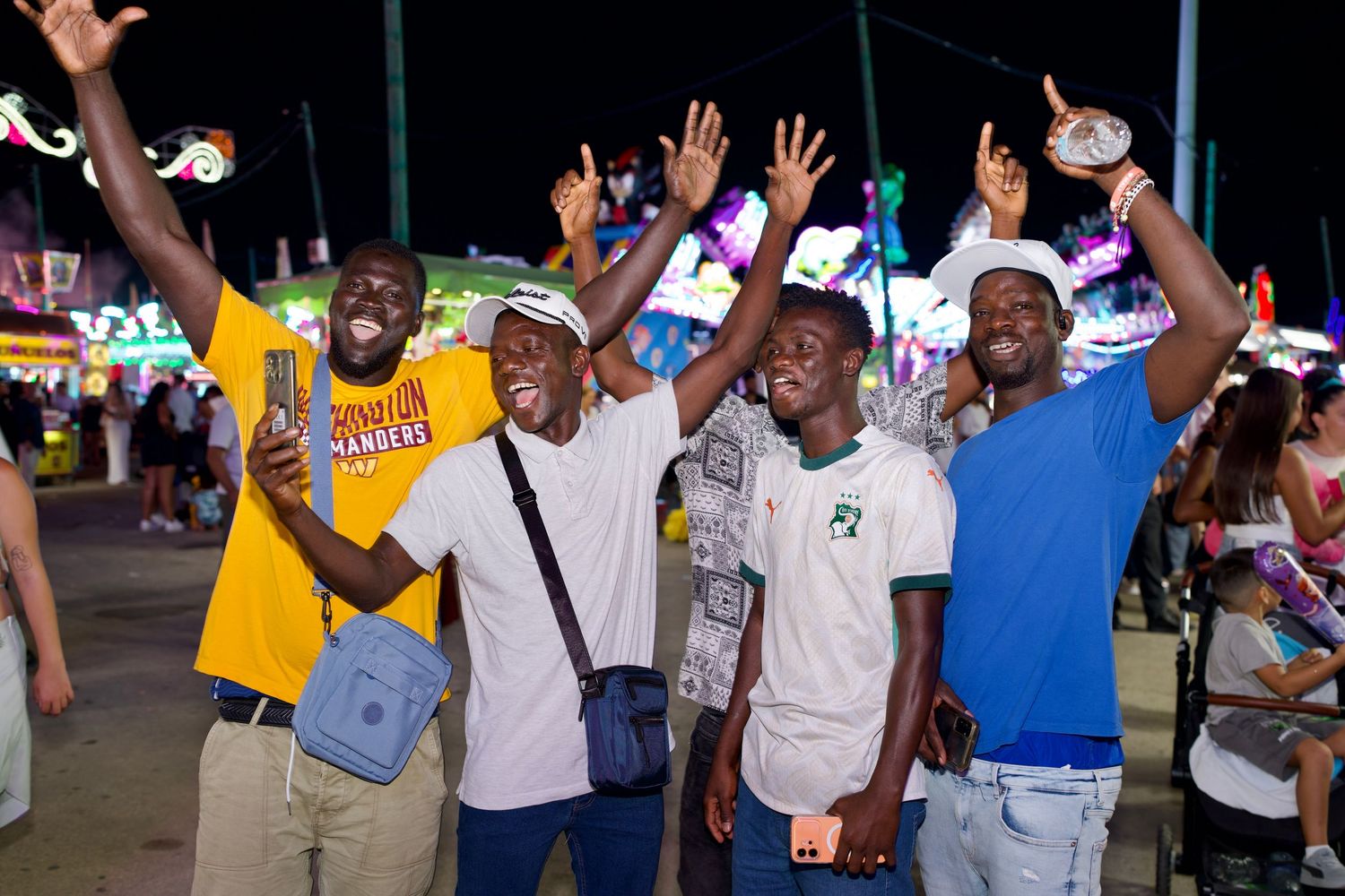 Energetic group of friends cheering at night during Feria de Málaga / Grupo de amigos celebrando con entusiasmo en la Feria de Málaga