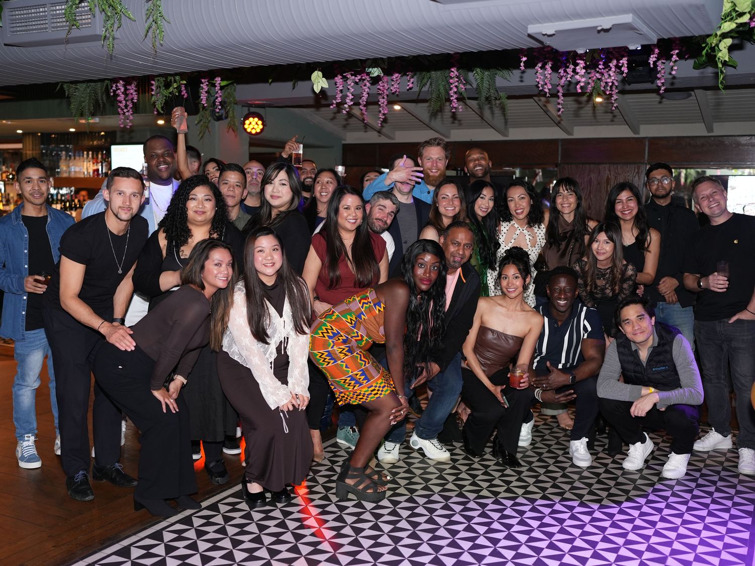 Large group of guests posing together at indoor London venue event by ARIETA Studios.