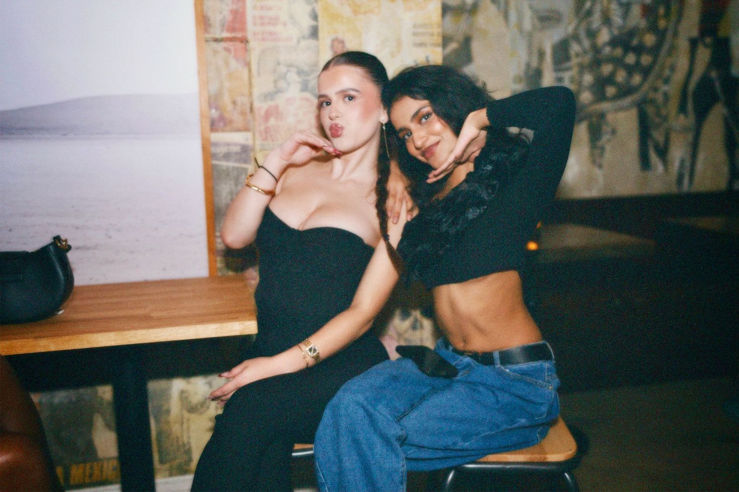 Two friends posing together on stools at London venue event by ARIETA Studios.