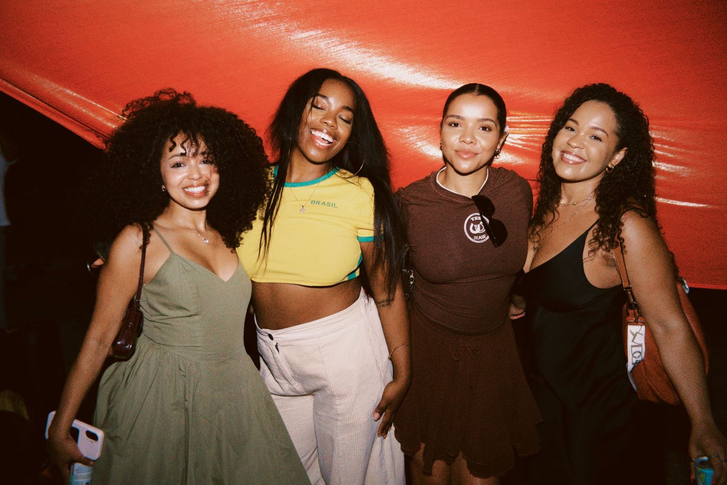 Four women posing together in stylish outfits at party by ARIETA Studios.