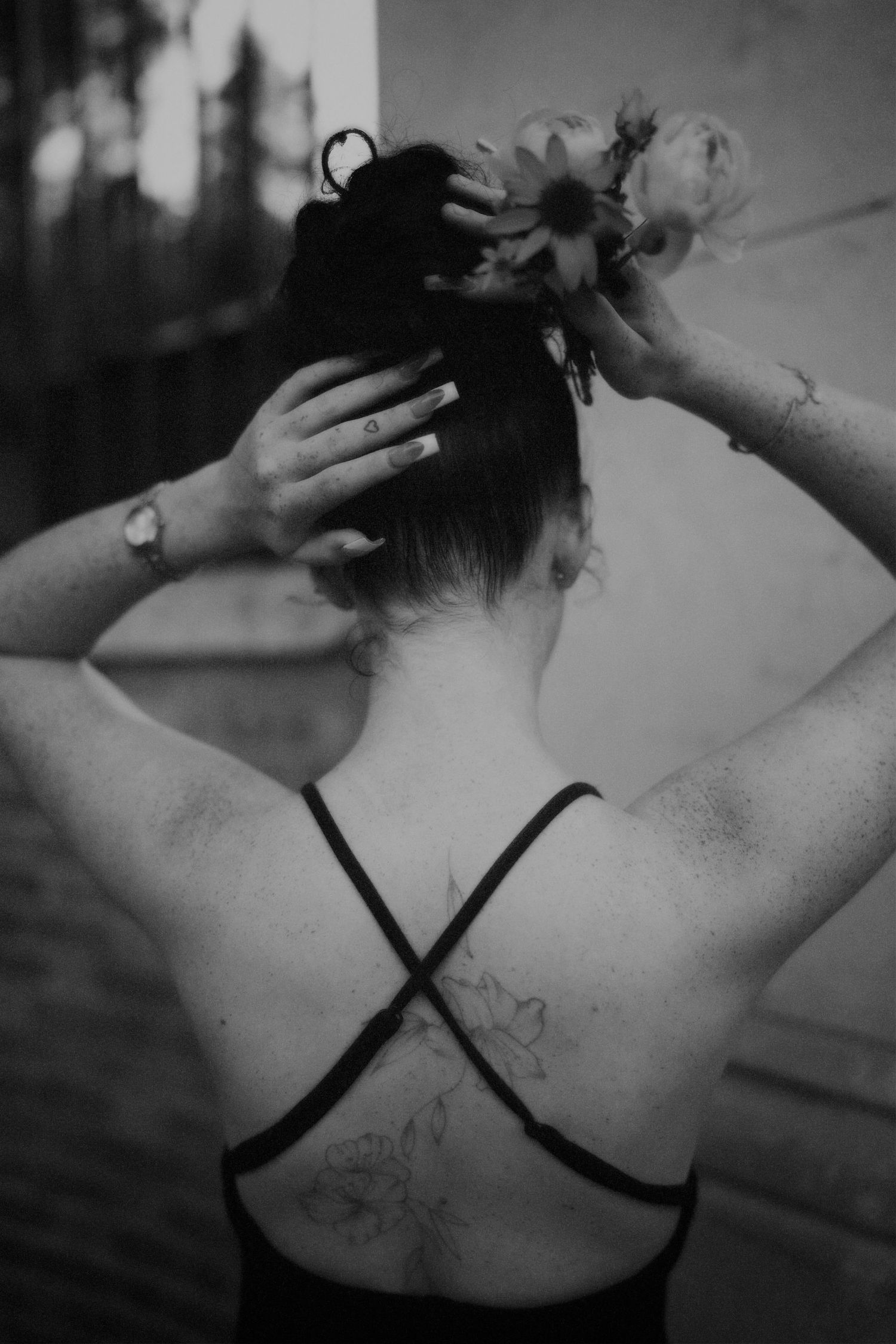 Black-and-white shot of a woman from behind, showing her back tattoo.