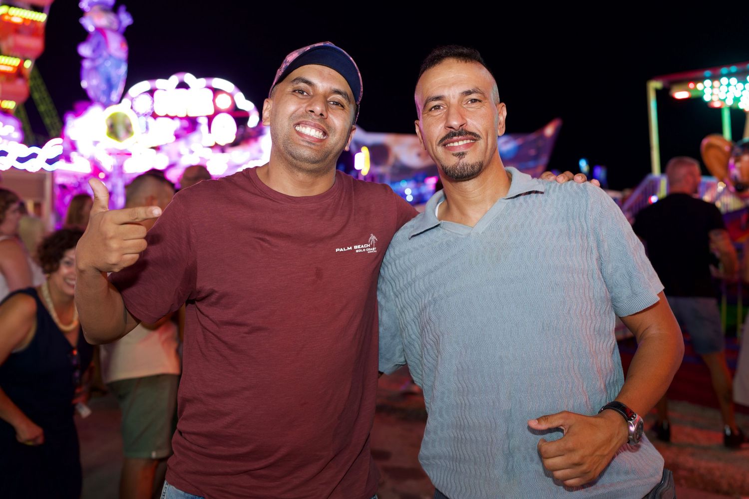 Two friends smiling together by fairground rides in Málaga / Dos amigos sonriendo juntos frente a las atracciones en Málaga