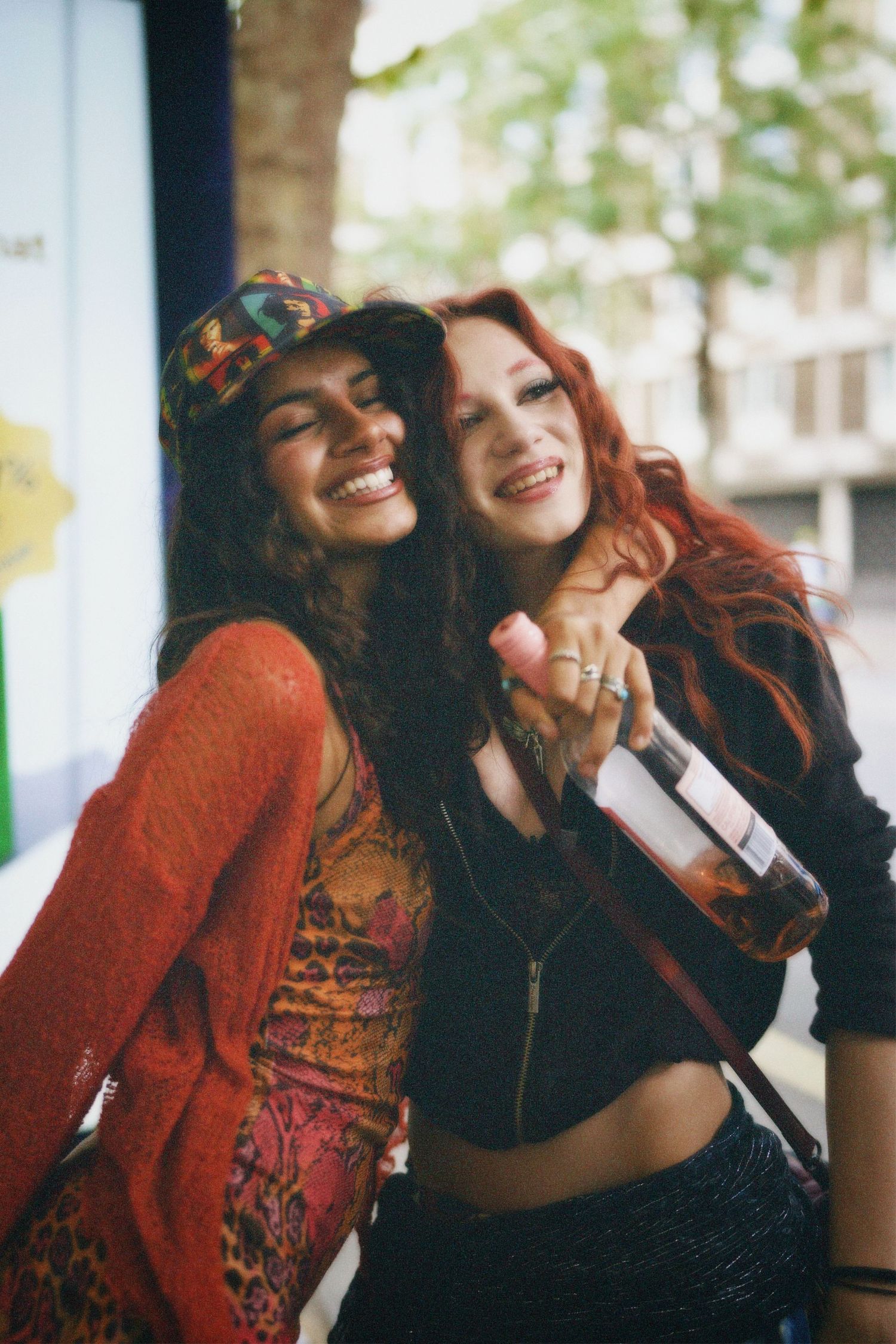 Close-up candid portrait of two friends laughing together in colourful carnival outfits.