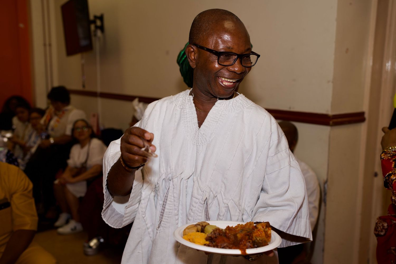 Guest in traditional white attire enjoying cultural food at event by ARIETA Studios