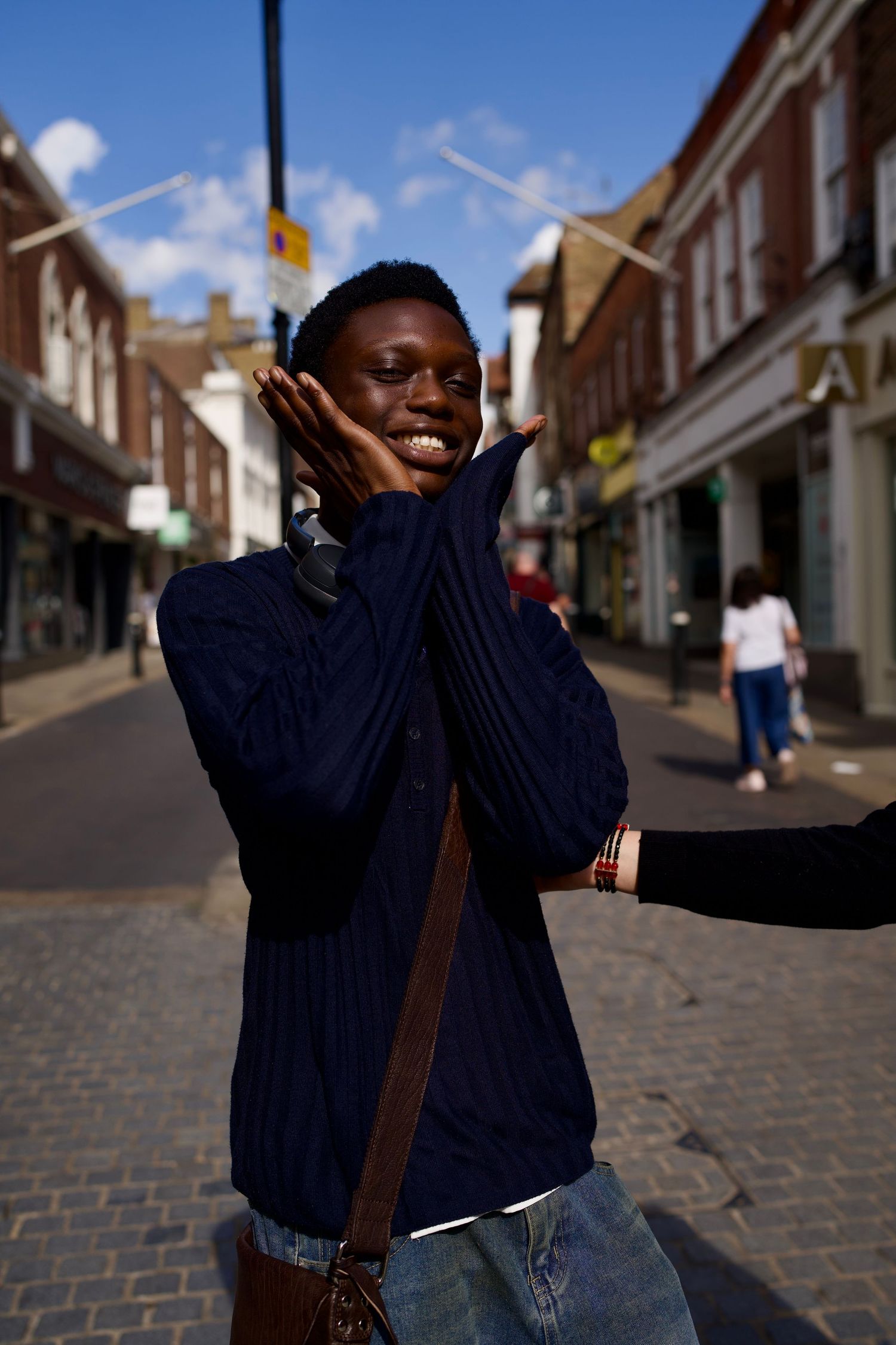 Candid street portrait of teen boy striking a fun pose on a sunny Windsor street.