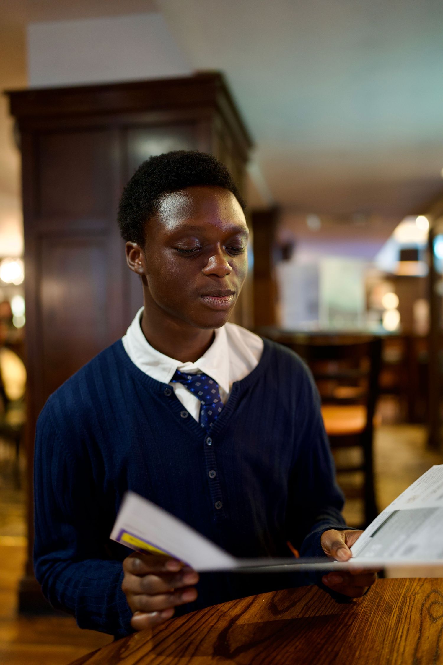 Young man reading the theatre programme inside a warm, classic Windsor pub.