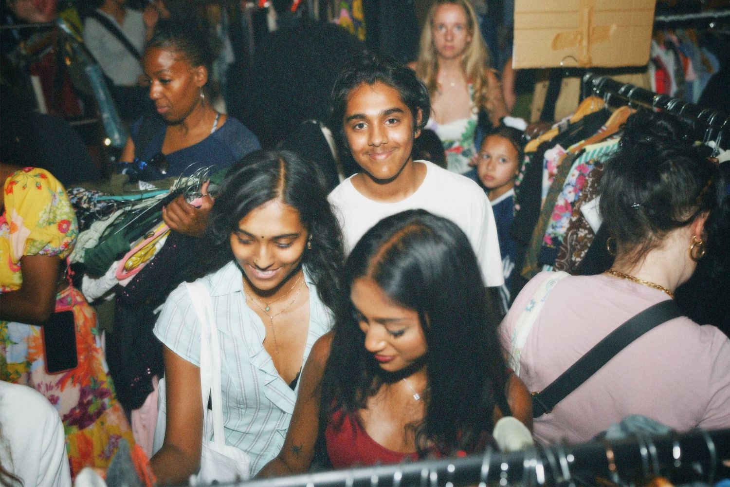 Crowd of stylish attendees browsing rails at the Fashion For Future clothing exchange