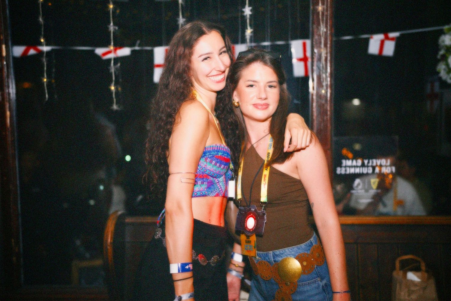 Two women posing together at London party with England flags background by ARIETA Studios.
