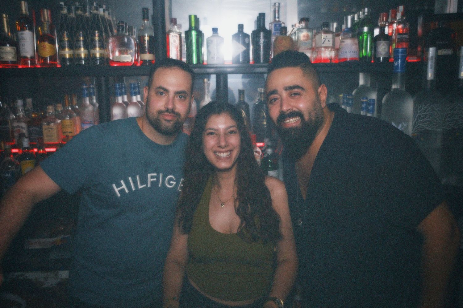 Team posing behind the bar counter. / Grupo posando juntos tras la barra de noche.