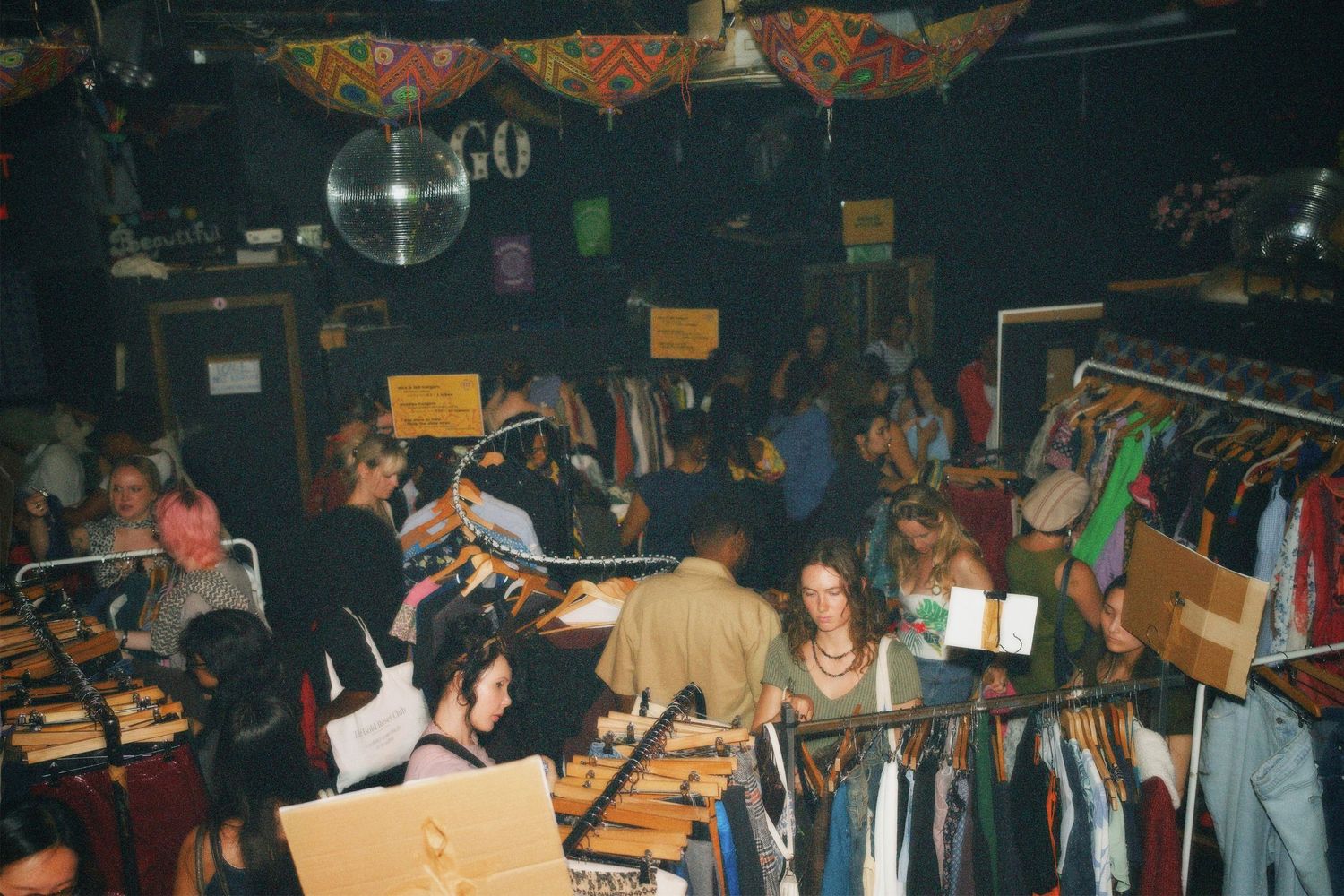 Busy crowd of shoppers exploring packed clothing racks inside the Fashion For Future swap
