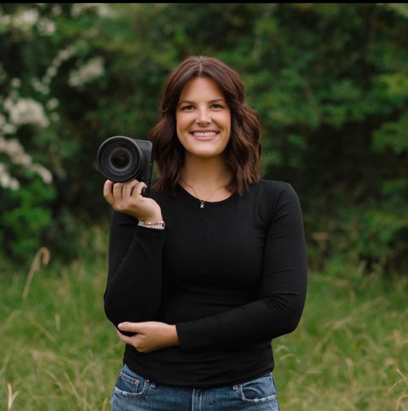 Victoria, North Alabama wedding photographer, holding her camera outdoors.