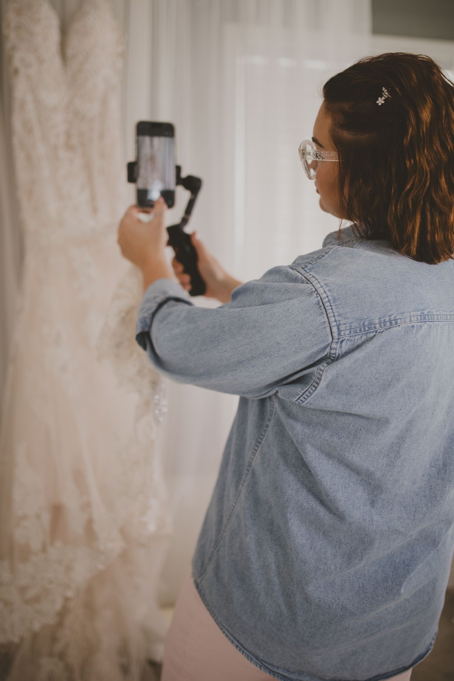 Wedding content creator filming behind-the-scenes wedding details with a smartphone and gimbal.
