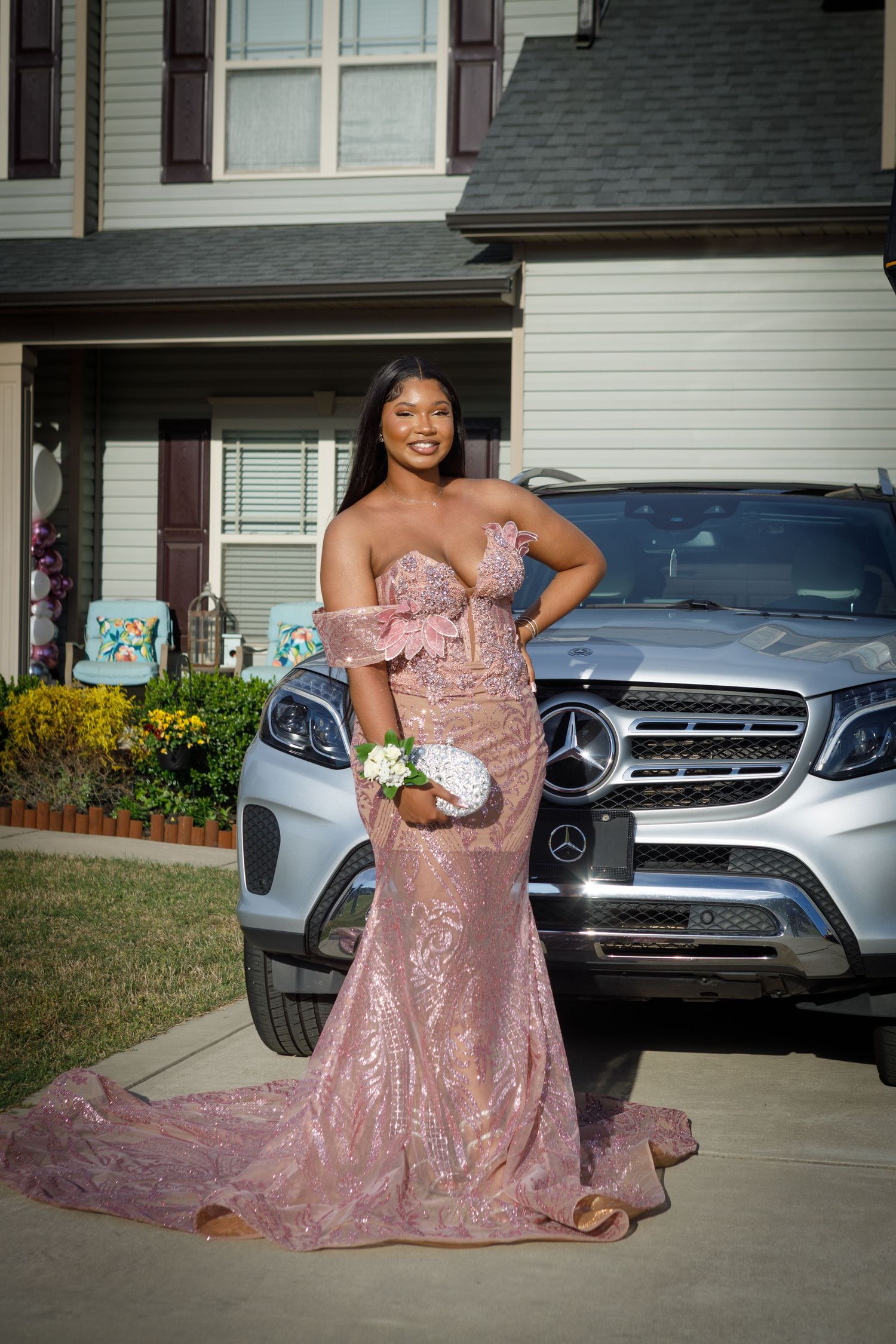 Young woman posed outdoors in a rose sparkly prom dress.