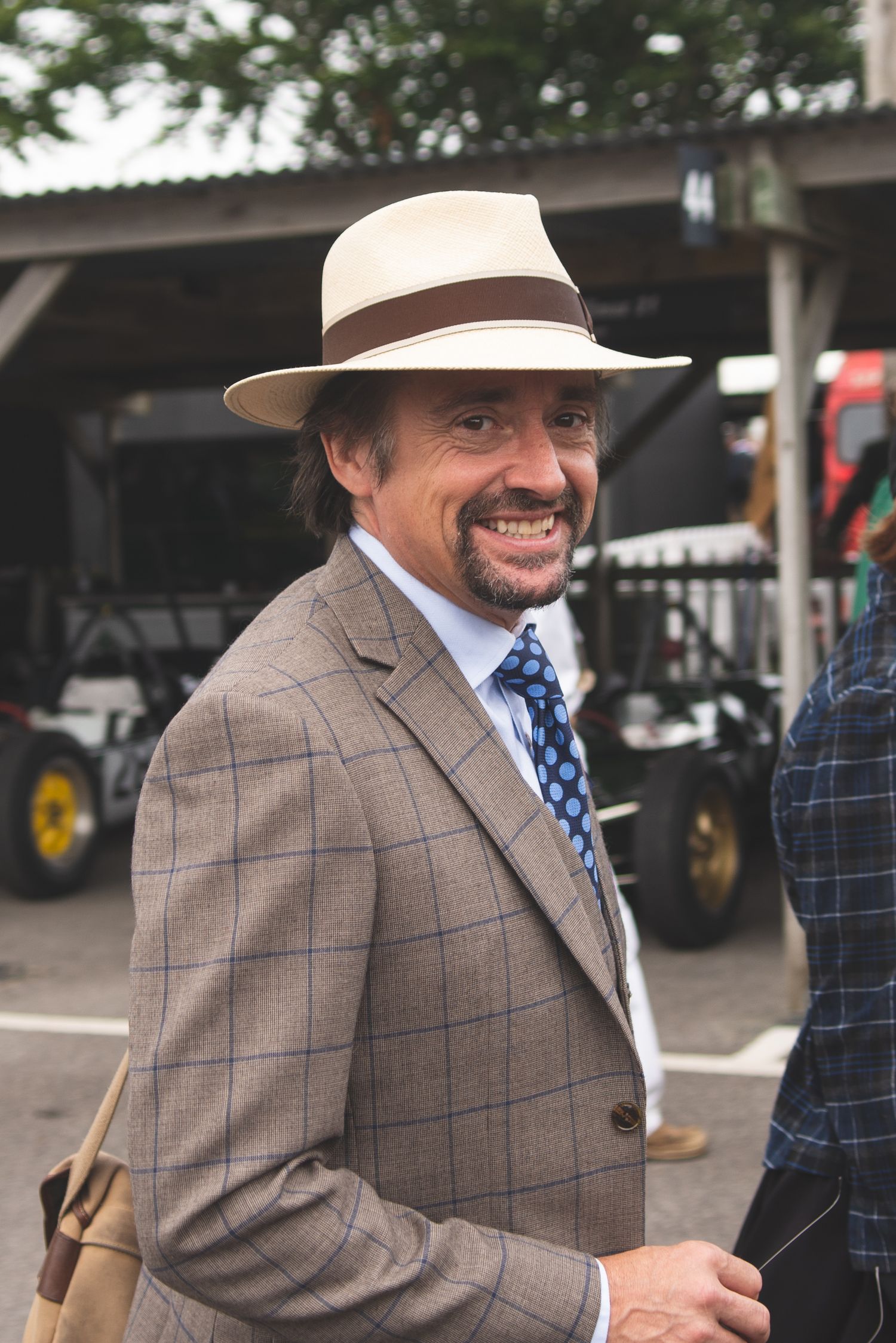 a smiling Richard Hammond in a panama hat and plaid suit at The Goodwood Revival.