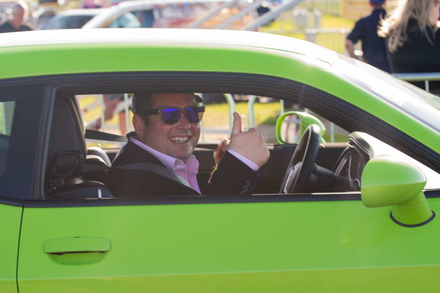 Man giving thumbs up from bright green sports car the british motoshow