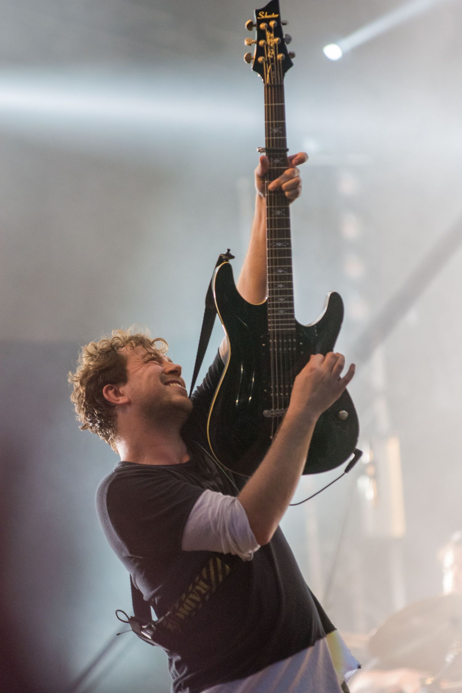 Busted's James Bourne raises black electric guitar overhead on stage during energetic live concert performance in Southend
