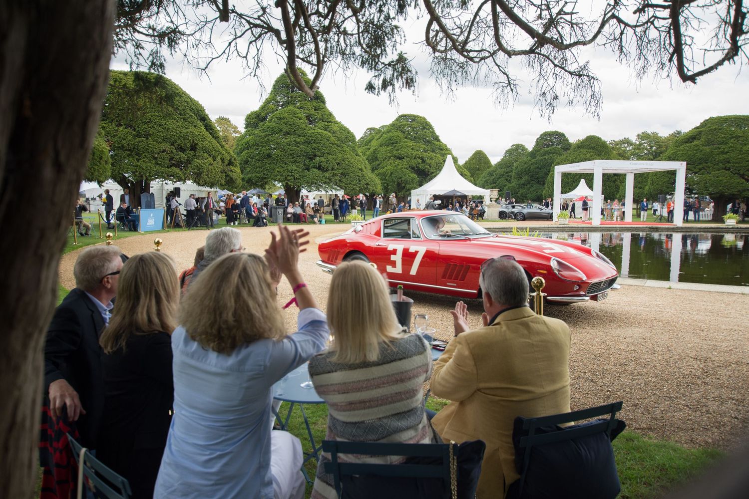 Spectators watch a classic red Ferrari 275 at Concours of Elegance at Hampton Court Palace.