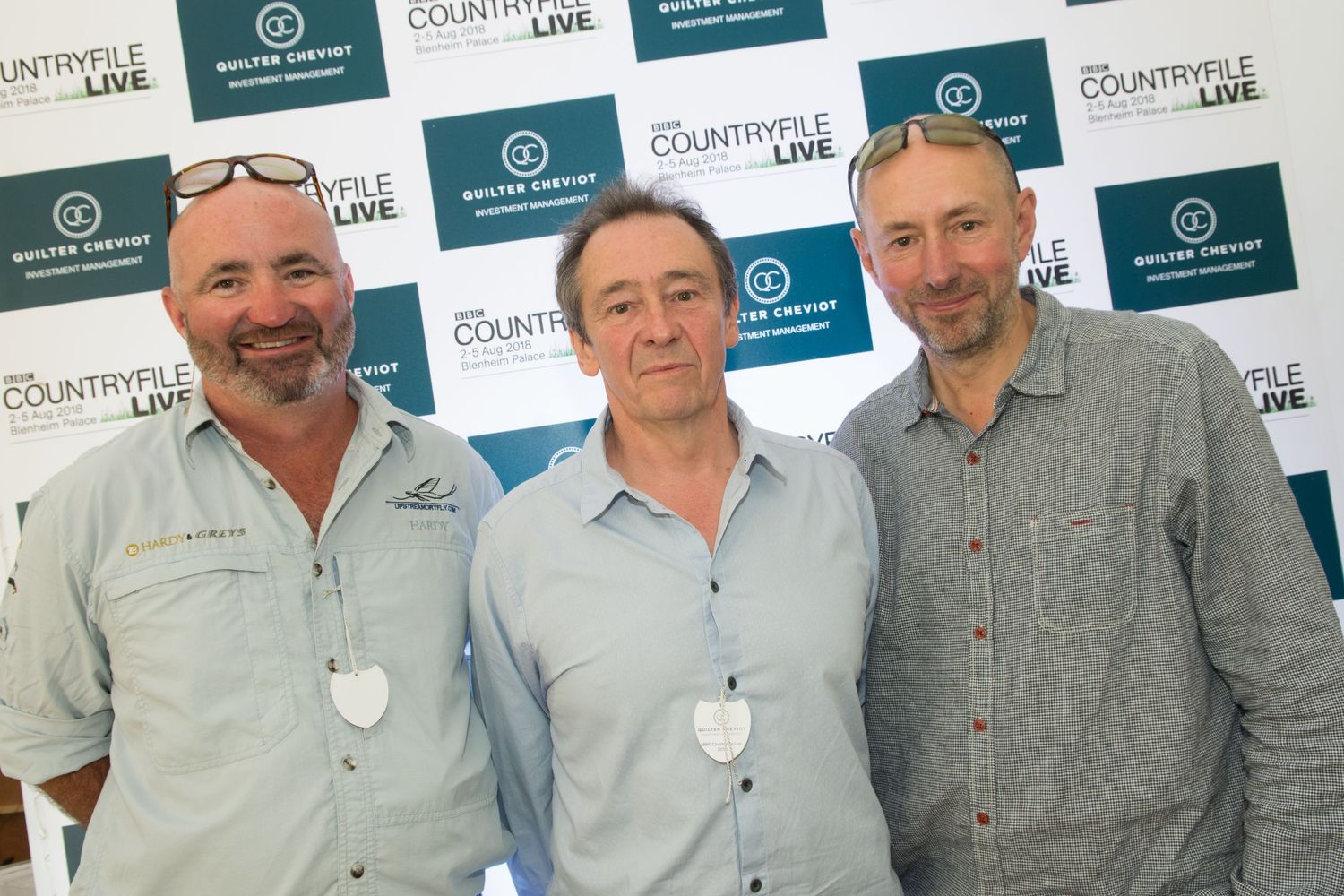 Three smiling men posing together at the Countryfile Live event backdrop.