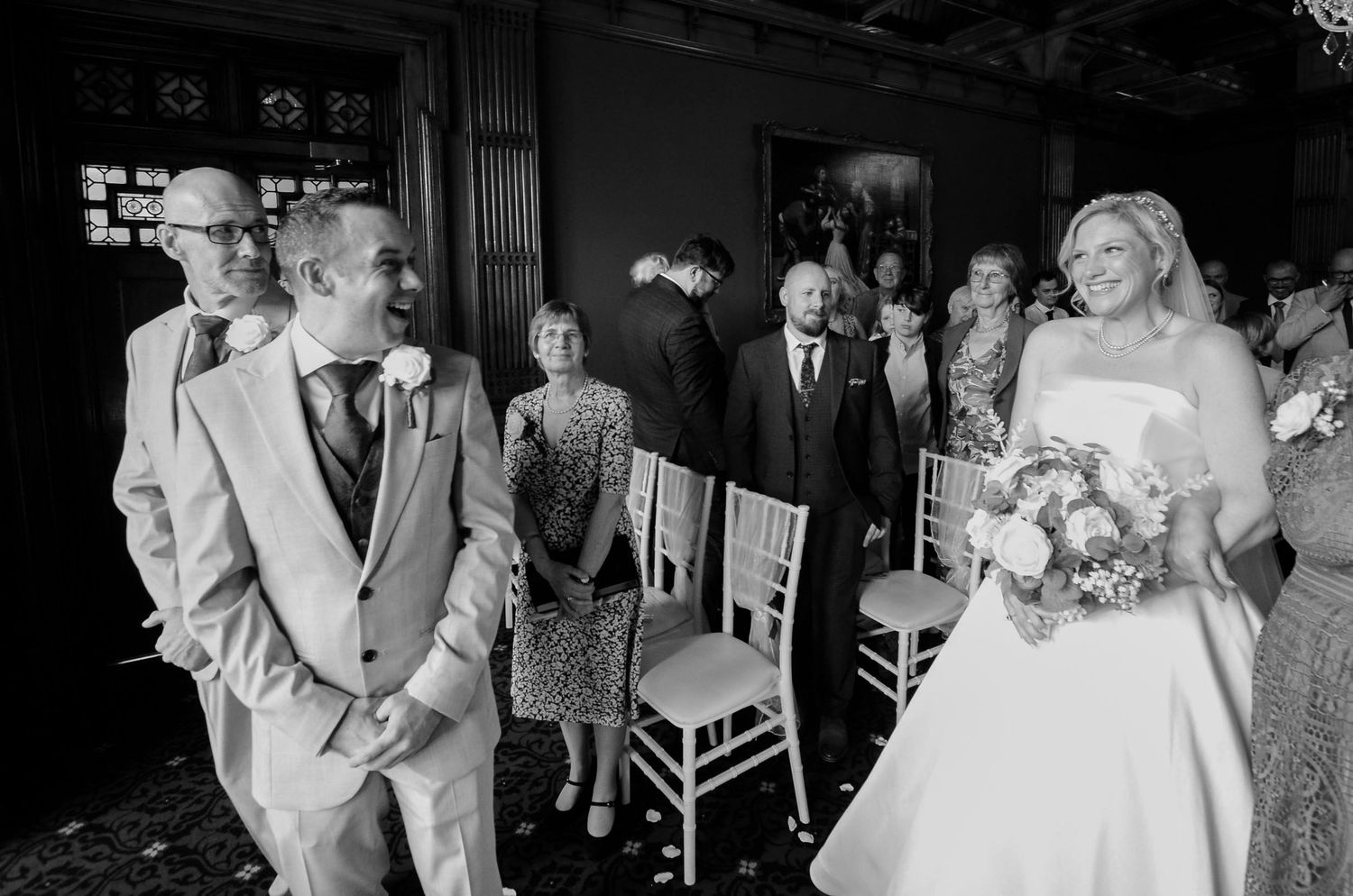Bride walks down the aisle in elegant white gown during indoor wedding ceremony.