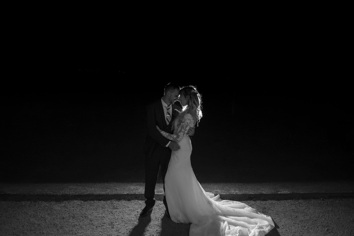 Romantic black and white photo of bride and groom kissing on a beach at night.