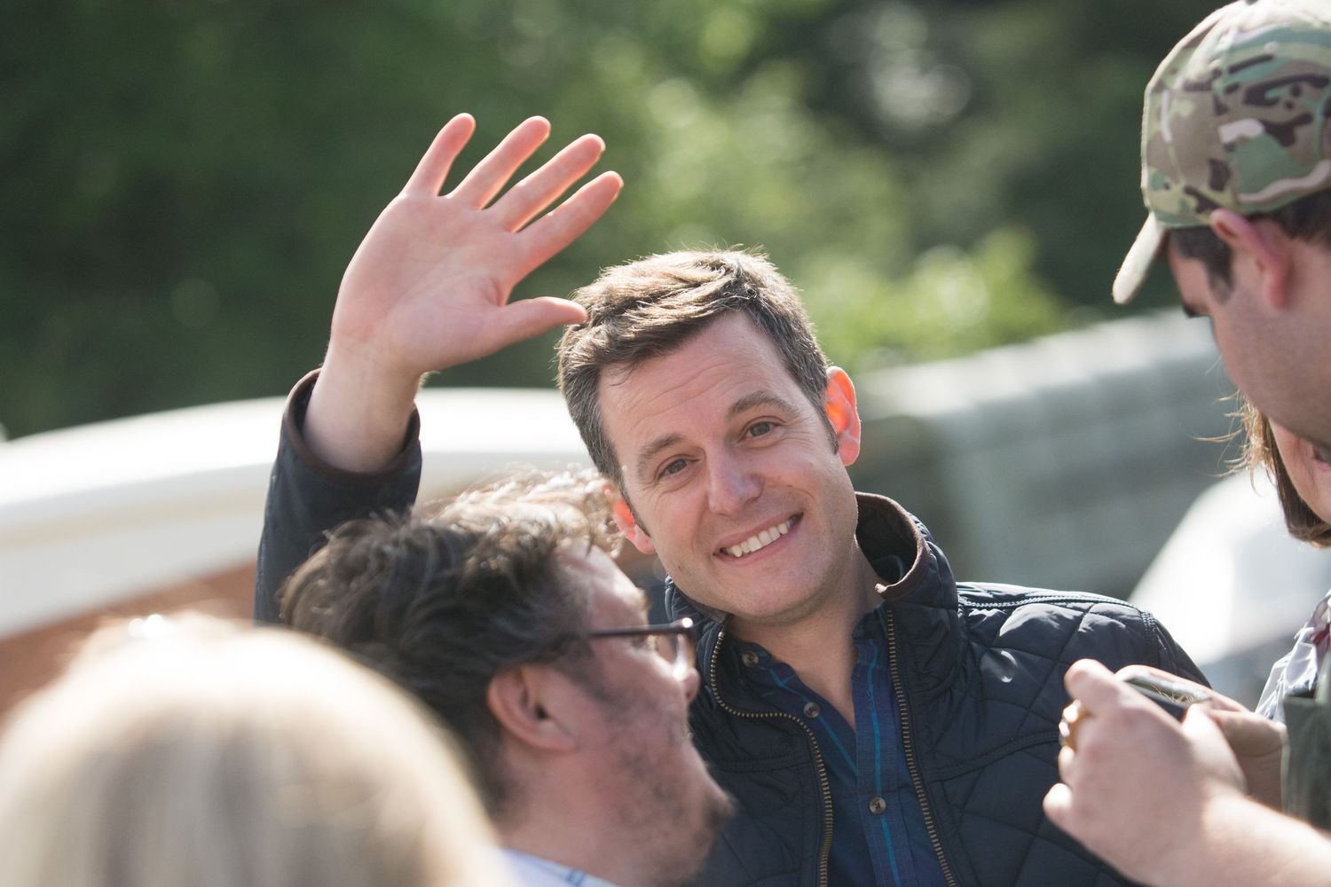 BBC presenter Matt Baker waving through a crowd at BBC Countryfile Live on a sunny day.