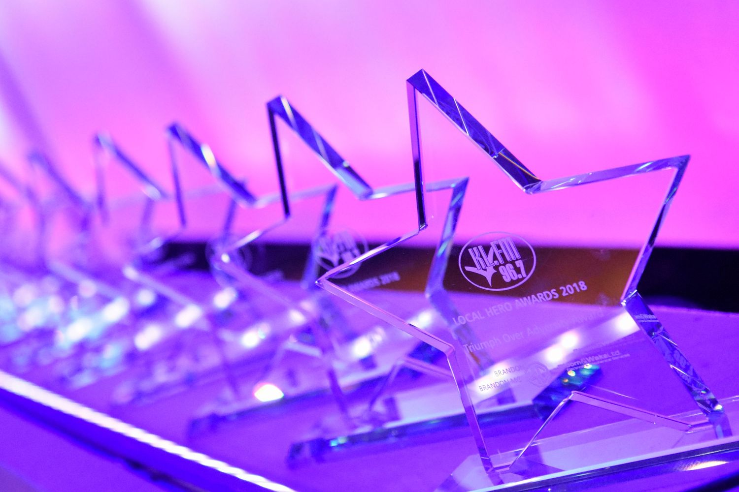 Crystal star-shaped awards trophies displayed under purple lighting at ceremony.