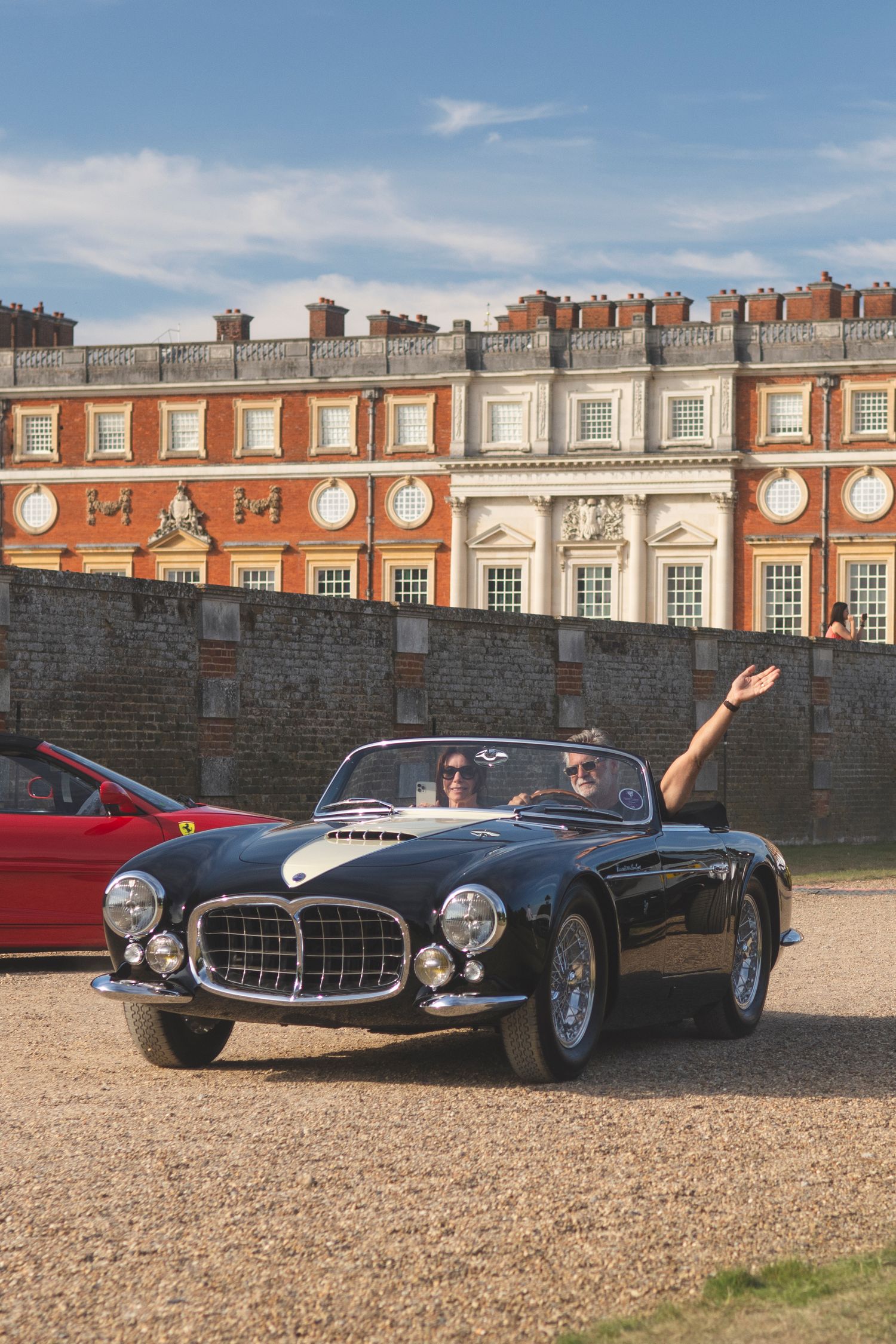Jonathan Segal waves from his  black 1956 Masarati a6gcs Frua leaving Concours of Elegance at Hampton court palace