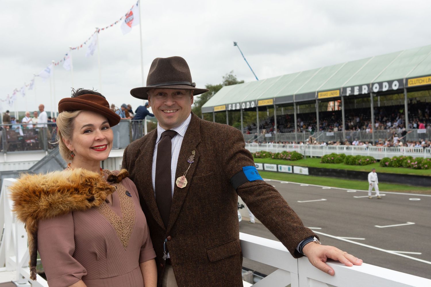 A stylishly dressed couple in vintage 1940s attire pose at the Goodwood Revival.