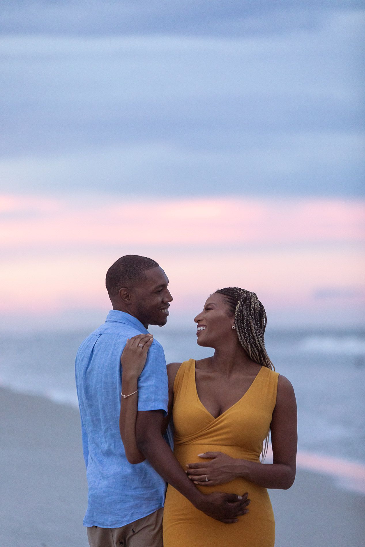pregnant woman posing for maternity photography in beach boardwalk with husband and children