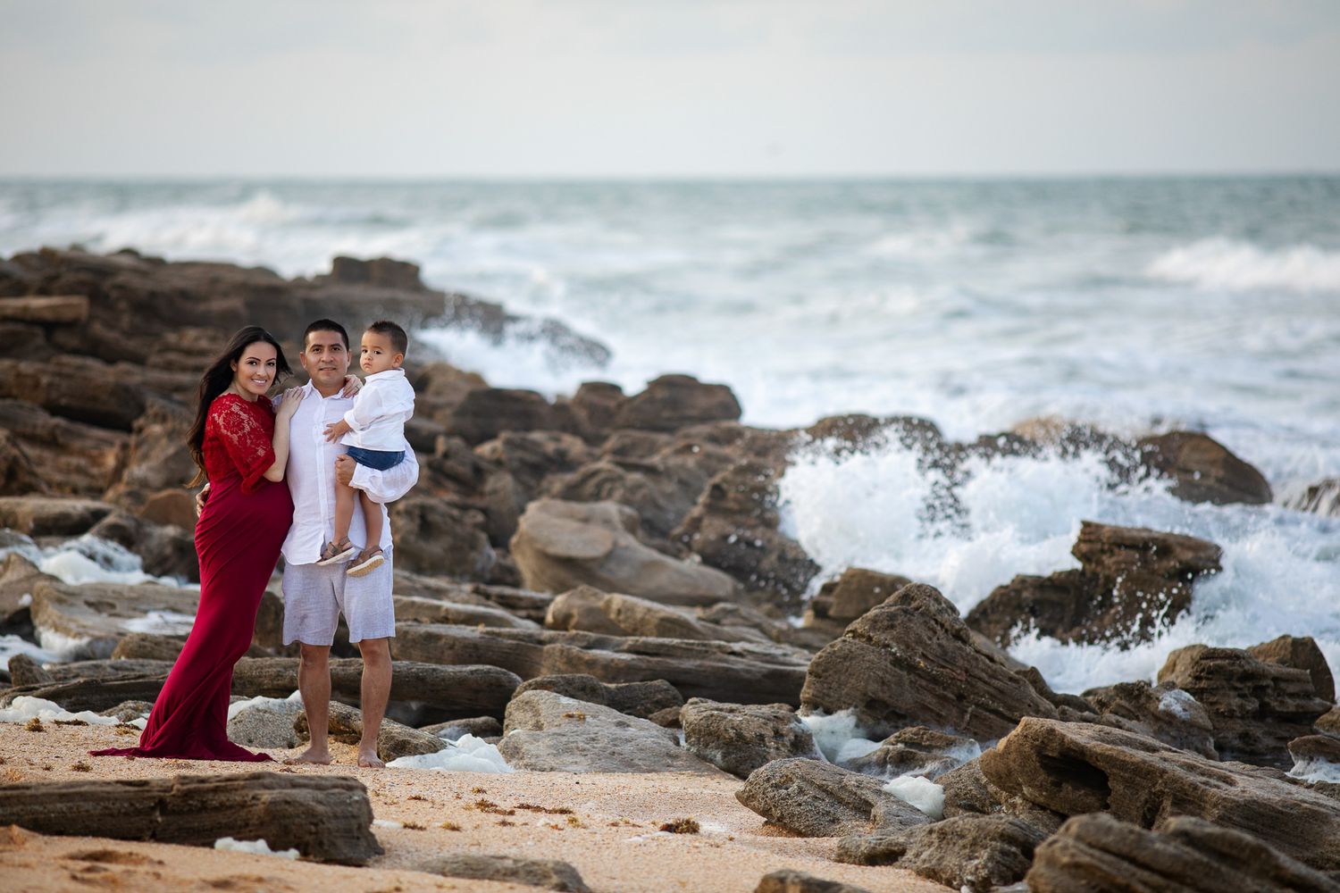 pregnant woman posing for maternity photography in beach boardwalk with husband and children