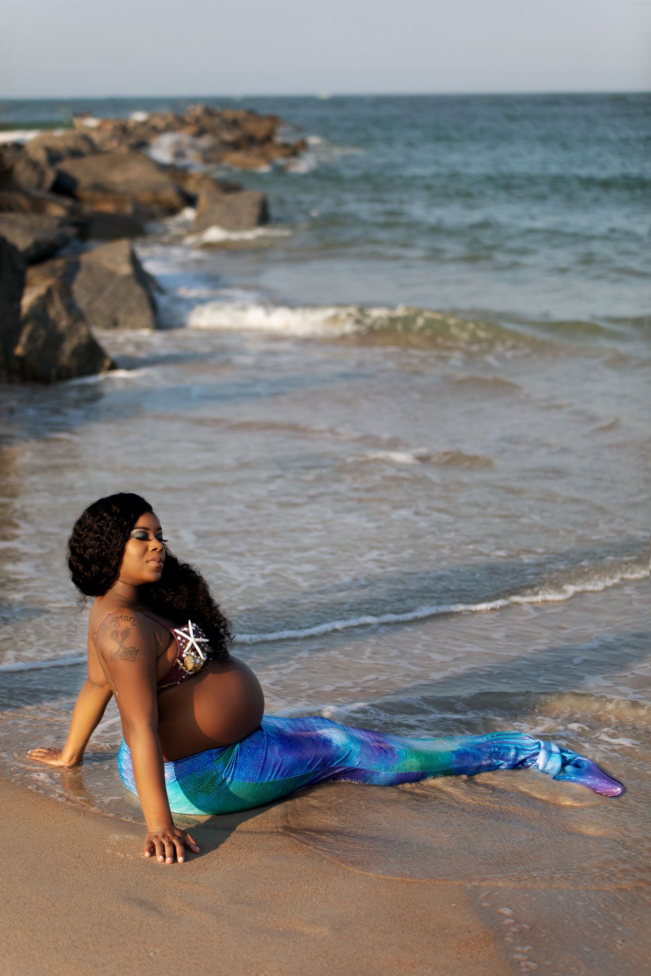 pregnant woman posing for maternity photography in beach boardwalk with husband and children
