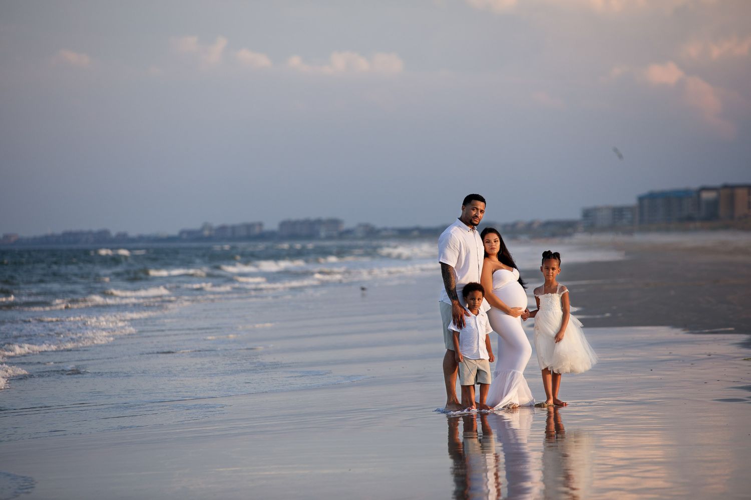 pregnant woman posing for maternity photography in beach boardwalk with husband and children
