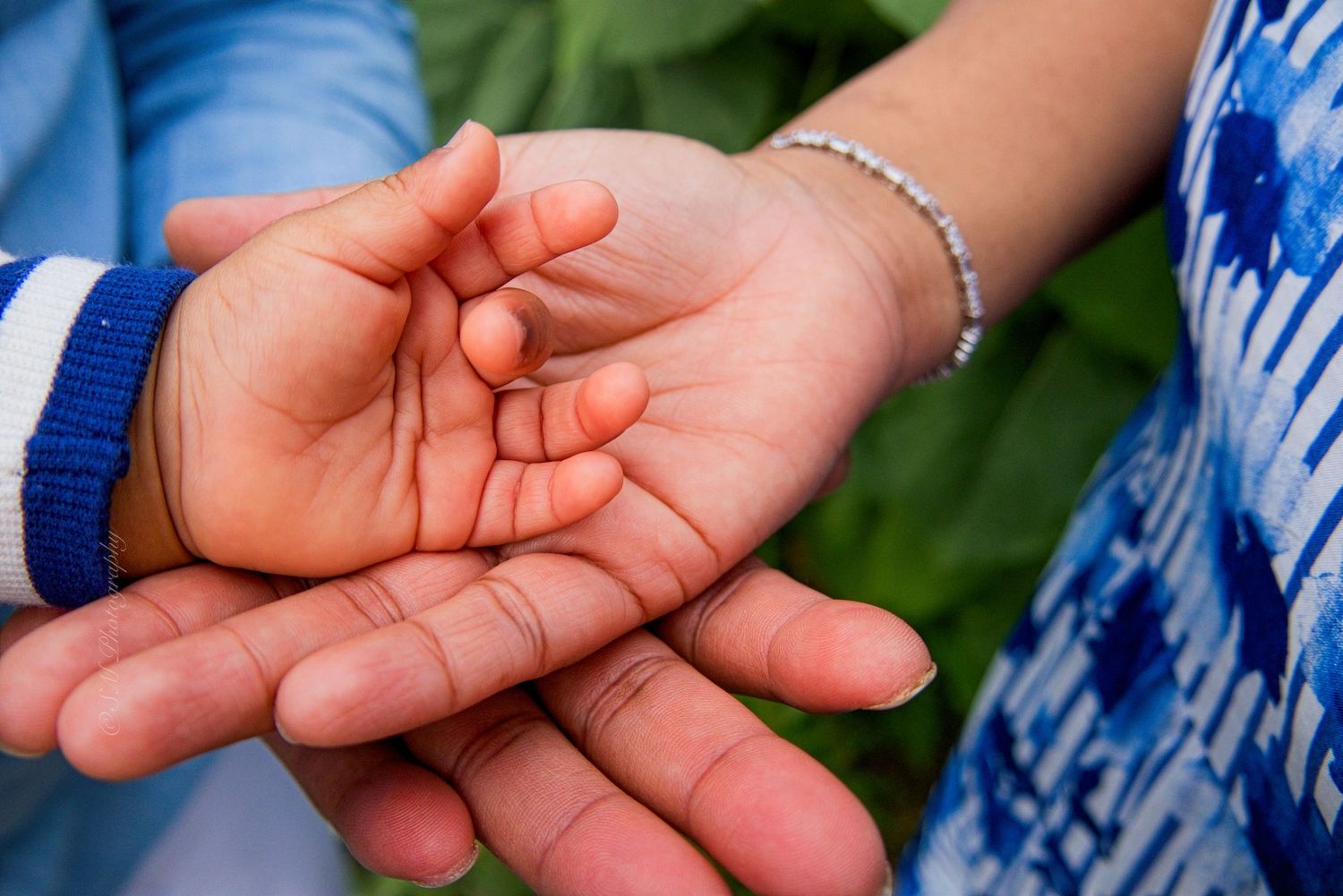 Three generations of hands rest together, symbolizing family love and connection outdoors.